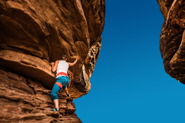 Women Climber practicing bouldering on a beautiful red rock in Canyonlands Utah USA
