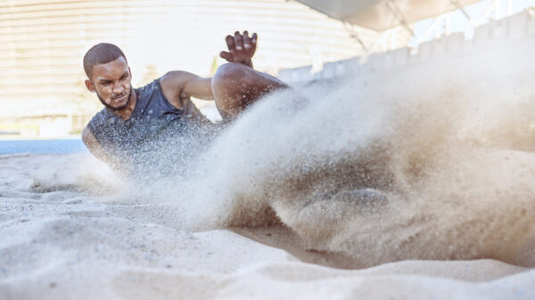 Man, athlete and sand for long jump, sport and training for sports, field and global competition. Sport, motivation and goal for podium, winning and world record for jumping at arena, stadium or park.